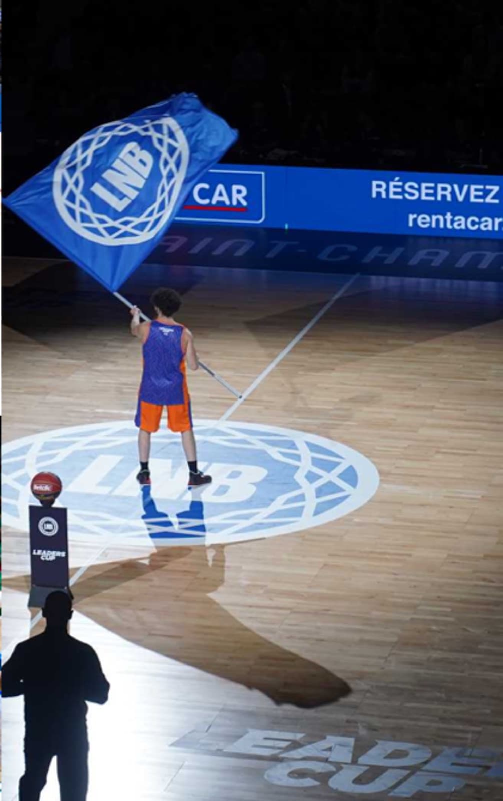 Porte-drapeau LNB au centre du terrain lors d'un match sponsorisé par Rent a Car